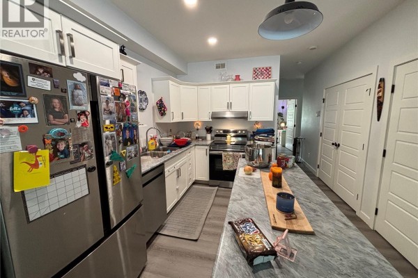 Kitchen with white cabinets, stainless steel appliances, and a grey marble island. - 24 A & B 2nd Avenue, Clavet