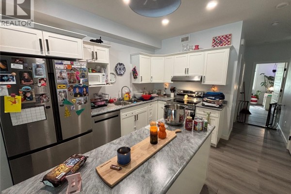 Kitchen with white cabinets, stainless steel appliances, and a grey marble island. - 24 A & B 2nd Avenue, Clavet