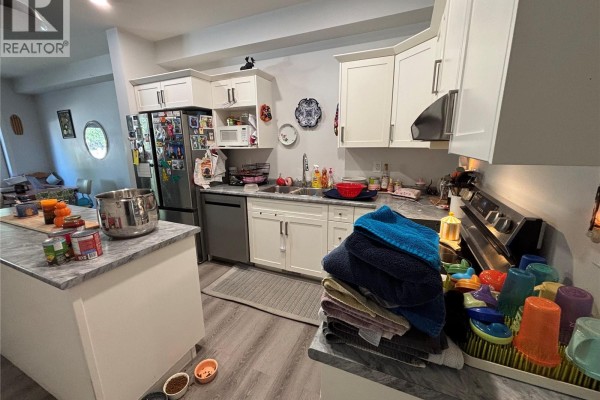 Kitchen with white cabinets, stainless steel appliances, and a grey marble island. - 24 A & B 2nd Avenue, Clavet