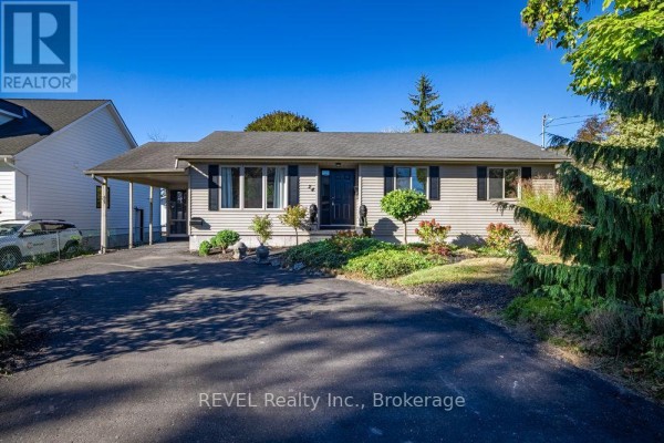 Backyard of a house with a dark wooden deck, a pond with decorative rocks, and lush landscaping. - 24 Adelaide Street, Fort Erie