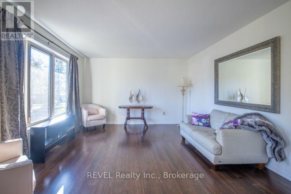 Overhead view of multiple houses and their yards, including a long backyard with a pond and surrounding greenery. - 24 Adelaide Street, Fort Erie