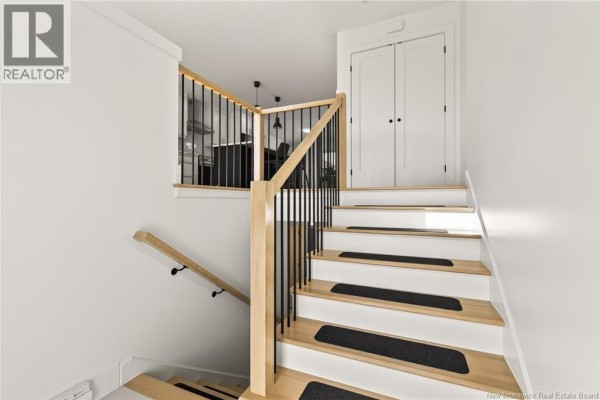 View of staircase with wooden handrail and closet doors at the top - 24 Adéo-rose, Memramcook