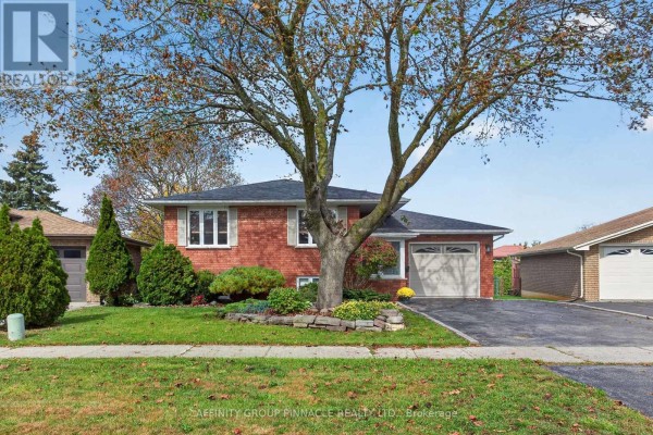 Side exterior of a red brick bungalow with a paved driveway and green lawn. - 24 Andrew Drive, Kawartha Lakes