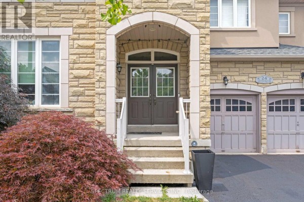 Covered front entrance with double glass doors, stone accents, and a white railing. - 24 Aristocrat Road, Brampton