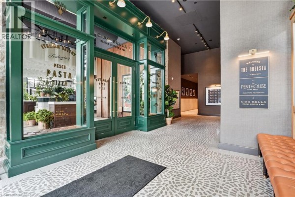Building lobby with a modern bench, textured walls, and directional signage. - 24 Augusta Street Unit# 302, Hamilton