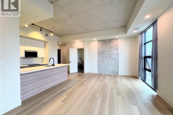 Open-concept living space with a kitchen island, modern cabinetry, and concrete ceiling. - 24 Augusta Street Unit# 302, Hamilton