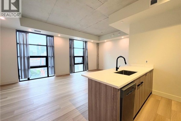 View of the living area and kitchen island with large windows overlooking the city. - 24 Augusta Street Unit# 302, Hamilton