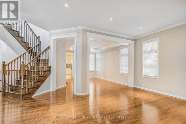 Living room with hardwood floors, wooden staircase, and view into dining area. - 24 Bellhouse Place, Whitby