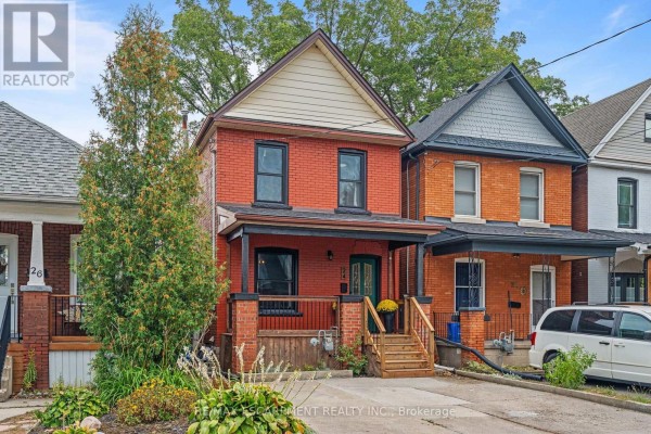 Exterior view of a red brick house with a covered porch, light siding, and mature trees. - 24 Belview Avenue, Hamilton