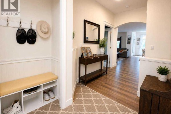 Entrance hall with a bench, shoe storage, coat hooks, and a console table with decor. - 24 Brander Avenue Nw, Langdon