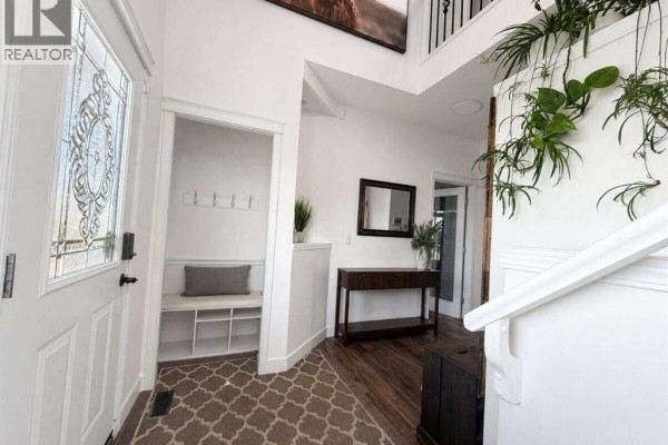 Staircase landing with a coat rack, plants, and carpeted steps leading upstairs. - 24 Brander Avenue Nw, Langdon