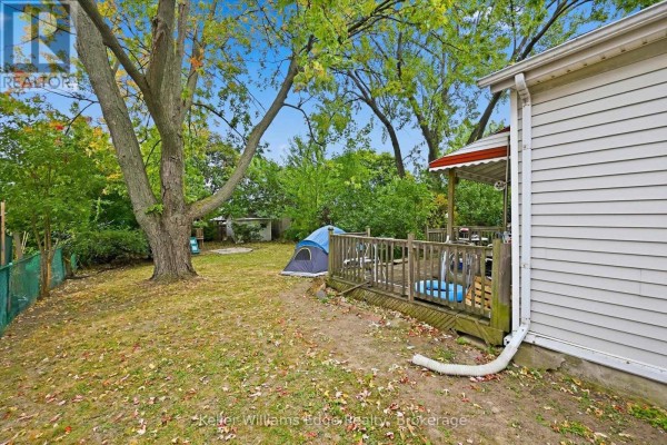 Backyard with a wooden deck and a blue tent set up on the grass. - 24 Brucedale Avenue W, Hamilton