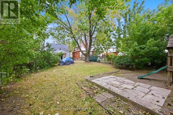 Spacious backyard with a paved area, a tent, and a children's play structure. - 24 Brucedale Avenue W, Hamilton