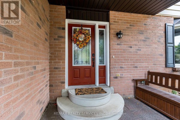 Close-up of the red front door with a wreath, surrounded by brick and a wooden bench. - 24 Carberry Road Street, Erin