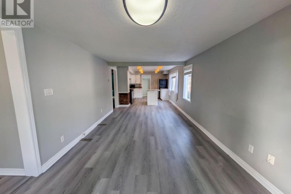 Open-concept living room with gray floors, kitchen island, and white cabinets - 24 Churchill Street St Catharines