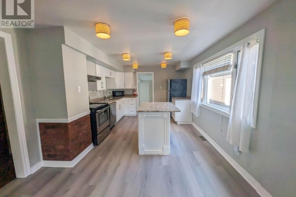 Kitchen with island, white cabinets, and stainless steel appliances - 24 Churchill Street St Catharines