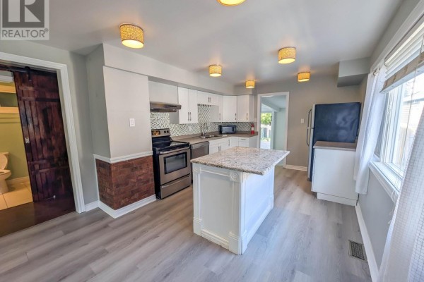 Renovated kitchen with island, stainless steel appliances, and barn door - 24 Churchill Street St Catharines