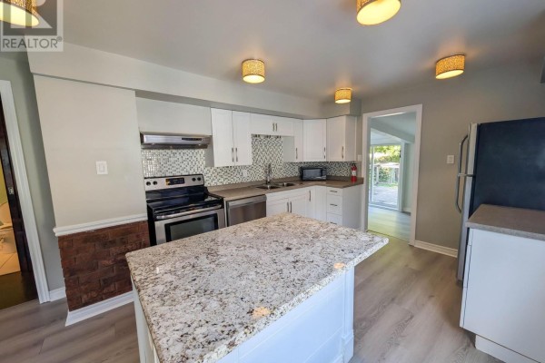 Renovated kitchen with granite island, white cabinets, and SS appliances - 24 Churchill Street St Catharines