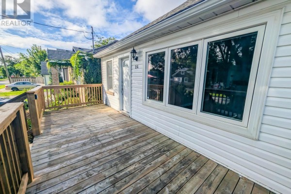 Side view of a white house with a wooden deck and large windows overlooking the street. - 24 Churchill Street, St  Catharines