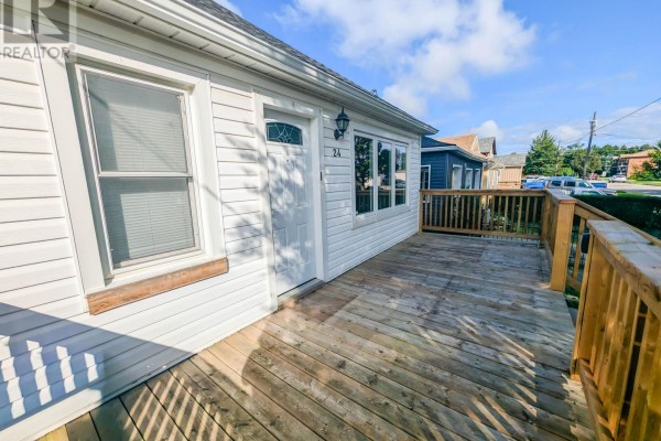 Wooden deck with railings wraps around the side of a white house with large windows. - 24 Churchill Street, St  Catharines