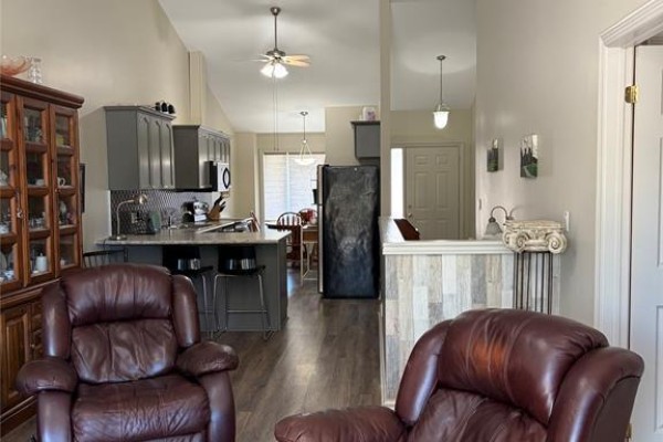 Living area with two leather recliners facing a partially visible kitchen and dining area. - 24 Erie Glen Crescent, Leamington