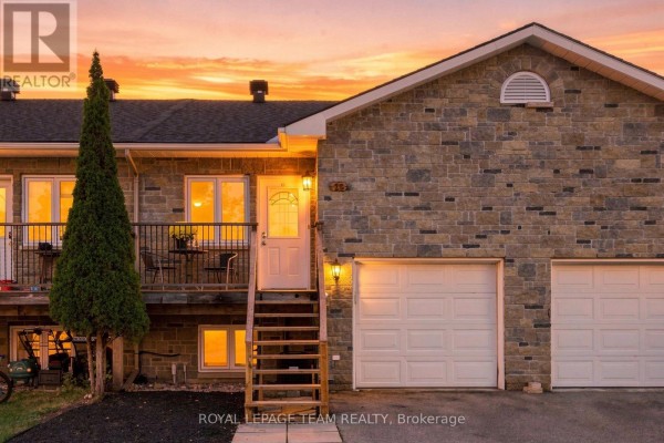 Townhouse exterior at dusk with illuminated windows and sunset sky. - 24 Farm Street, Mississippi Mills