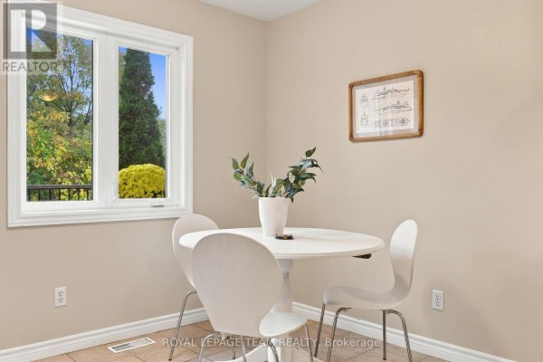 Close-up of dining area with white tulip table and chairs, and a window view. - 24 Farm Street, Mississippi Mills