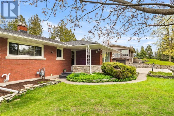 Side view of the brick house, showing the entrance porch and backyard. - 24 Grand Hill Drive, Kitchener