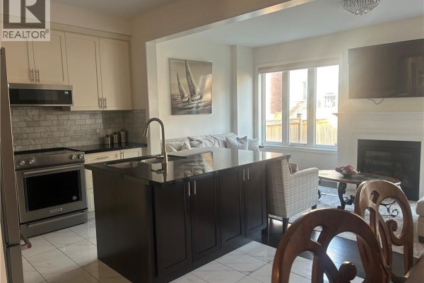 Kitchen with stainless steel appliances, a dark island, and an open view to the living room. - 24 Heming Trail, Ancaster
