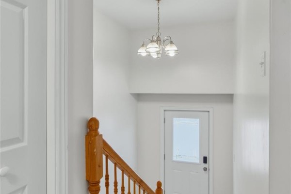 Interior view of a staircase with wood banister and white doors leading to a back entrance. - 24 Hopedale Crescent, St  John S
