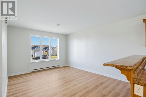 Living area with light wood laminate flooring, white walls, and a large window. - 24 Hopedale Crescent, St  John S
