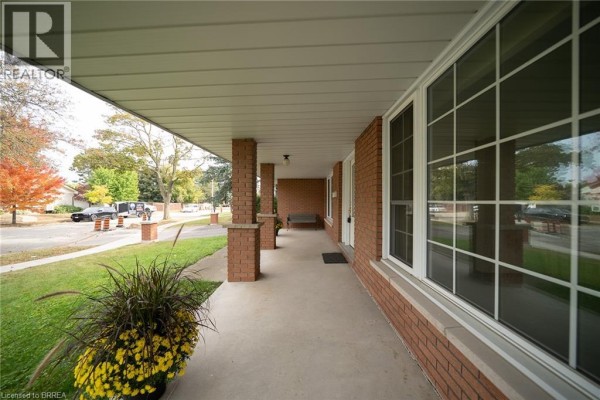 Covered front porch with brick pillars, large windows, and a view of the street. - 24 Japonica Crescent, Brantford
