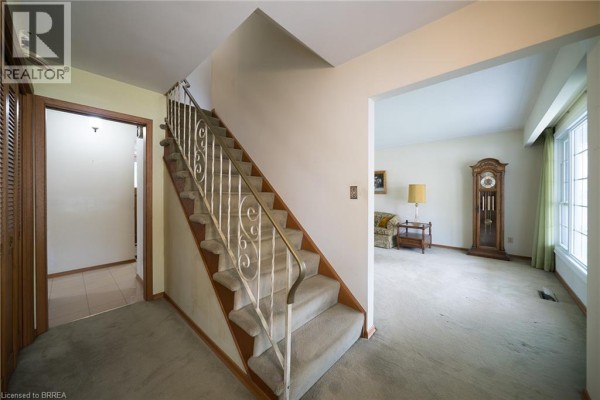 Interior entryway with a carpeted staircase, beige carpet, and a doorway leading to the living area. - 24 Japonica Crescent, Brantford