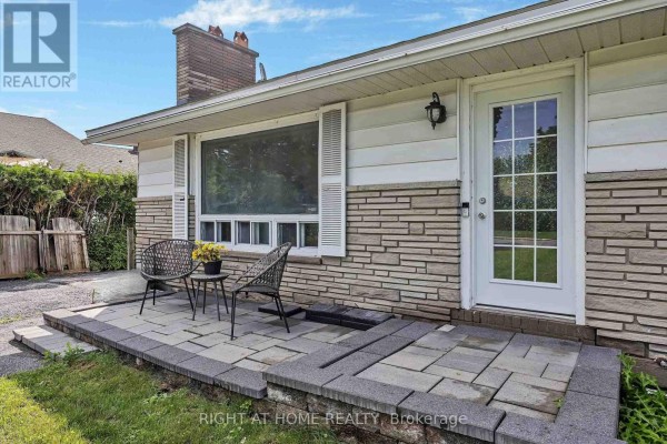 Wide angle view of the house and property from the street, showing a lawn and paved driveway. - 24 Largo Crescent S, Ottawa