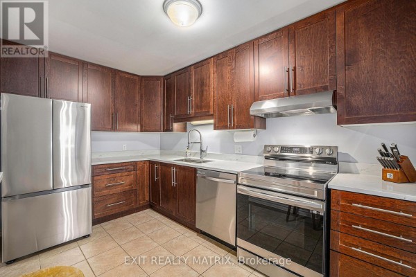 Open kitchen with dark wood cabinets, stainless steel appliances, and bar stools - 24 Oakhaven Private, Ottawa
