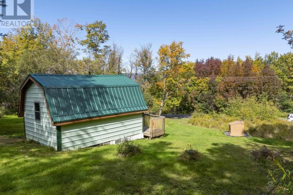 Small light-colored building with green metal roof and wood deck, surrounded by grass. - 24 Old Post Road, Smiths Cove