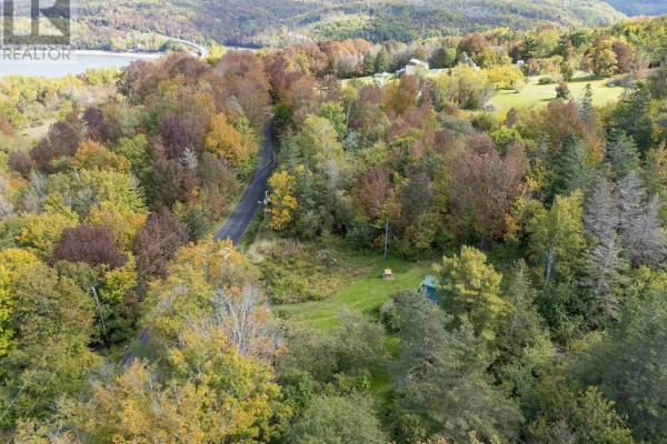 Aerial view of rural property with trees, winding road, and distant water. - 24 Old Post Road, Smiths Cove