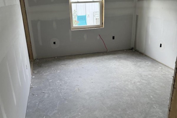 Unfinished room with drywall, concrete floor, and a single window. - 24 Peterson Street, Cambridge