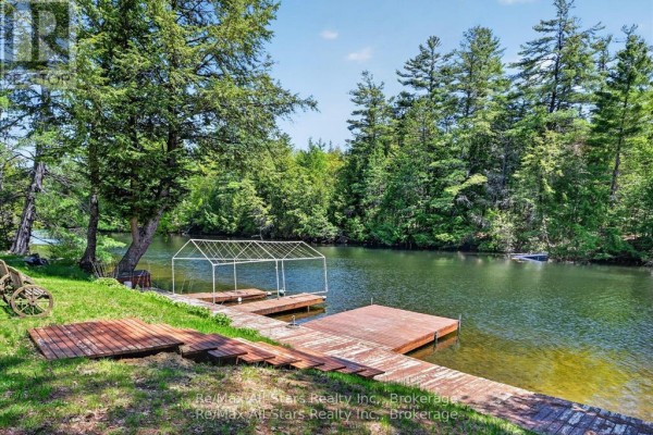 Wooden docks and a covered boat slip on the waterfront. - 24 Relax Avenue, Kawartha Lakes