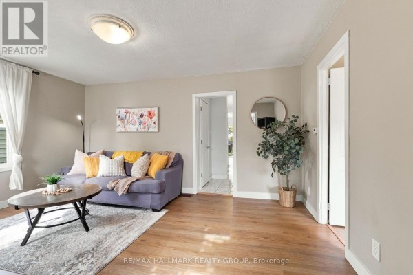 Living room with a purple sofa, coffee table, and wood flooring. - 24 Reuben Cr Crescent, North Grenville