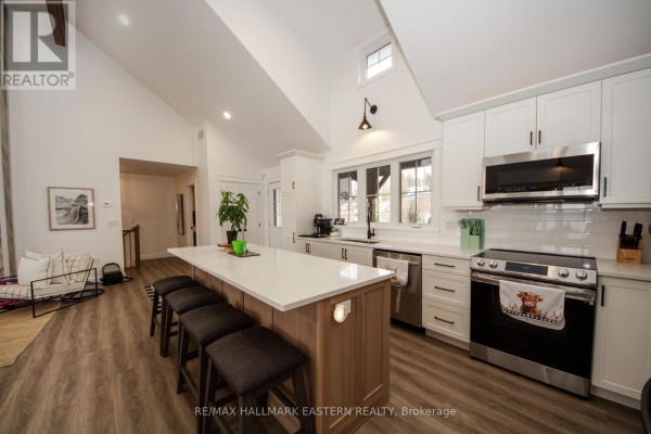 Kitchen and living area with a large sectional sofa, dining table, and vaulted ceiling with exposed beams. - 24 Rory Drive, Selwyn