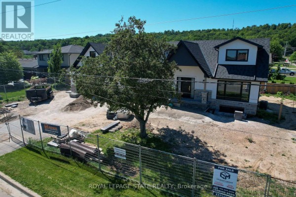 Construction site view of a modern house exterior with fencing, dirt piles, and landscaping materials. - 24 Royce Avenue, Hamilton