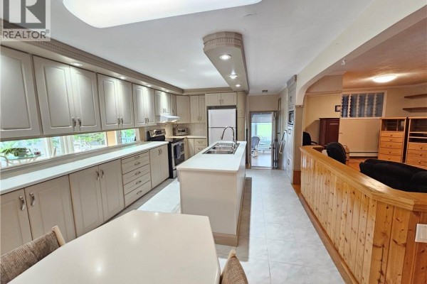 Kitchen with ample cabinet space, island, and view of dining area. - 24 Rue Veteran Sud, Grand Falls