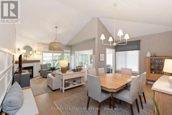 Open-concept living and dining area with a vaulted ceiling, fireplace, and wood floors. - 24 Sandpiper Key Way, Markham