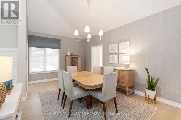 View of the dining area showing a wood table, chairs, textured wallpaper, and a window. - 24 Sandpiper Key Way, Markham