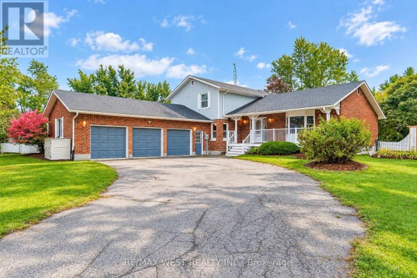 Front view of a brick house with a three-car garage, white porch, and lush green lawn. - 24 Smith Drive, Uxbridge