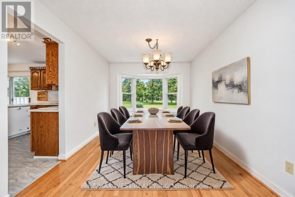 Dining room with hardwood floors, a bay window with a view of trees, and a table set for eight. - 24 Smith Drive, Uxbridge