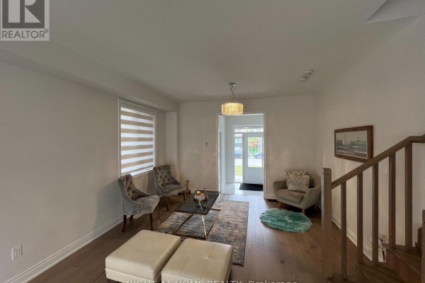 Living room with gray upholstered chairs, ottoman, coffee table, and wood flooring. - 24 Tamworth Terrace W, Barrie