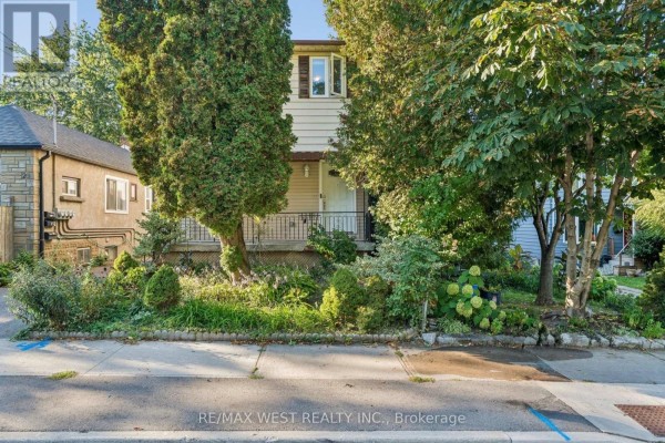 Front yard view of the house with mature trees, landscaping, and sidewalk. - 24 Victoria Street, Toronto