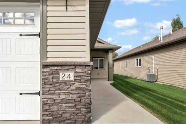 Close-up of house number 24 next to a stone-clad garage door and entryway. - 24 Wheatland Drive Se, Medicine Hat